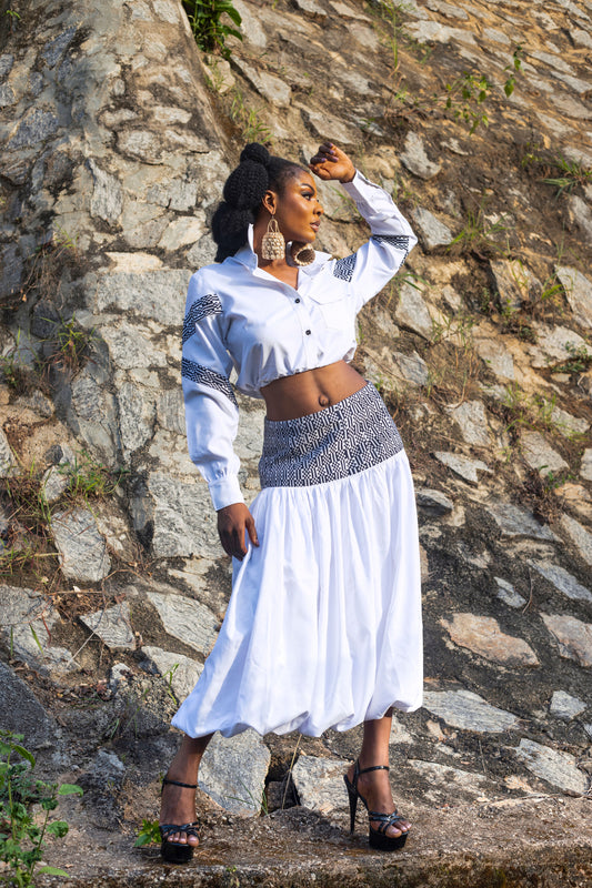 This Cynthia Abila designed two piece consist of a cropped stylish shirt paired with a bubble hem skirt. The shirt offers a comfortable fit with a classic collar and button down front. The bubble hem skirt is designed with a gathered, slightly puffed hemline giving a playful and feminine casual look.  Together, this ensemble combines comfort and style. It is made with white plain cotton and a woven cotton combination. Style this with a pair of heels and complement with simple accessories. Step out in style