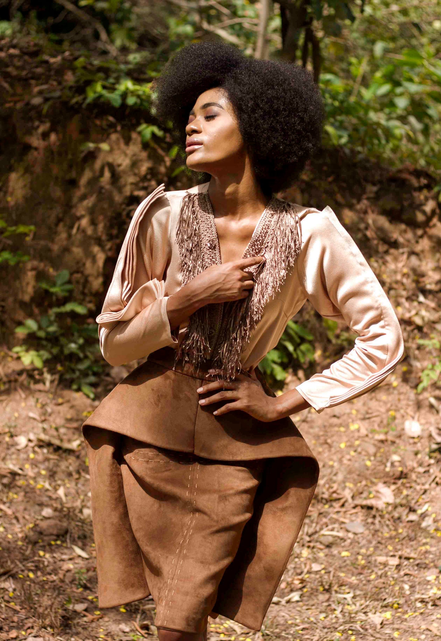 The Cynthia Abila Designed Fluff blouse is a Satin blouse with a shredded neckline detail and a slightly flared fit, also featuring a long fitted sleeves with dramatic pleats. Which pairs perfectly with  Winged skirt which is made from Suede leather with waistband and large winged attachment at the sides. Lined underneath with 100% polyester Lining and has zip fastening at the back. The front features hand stitched designs with precision.